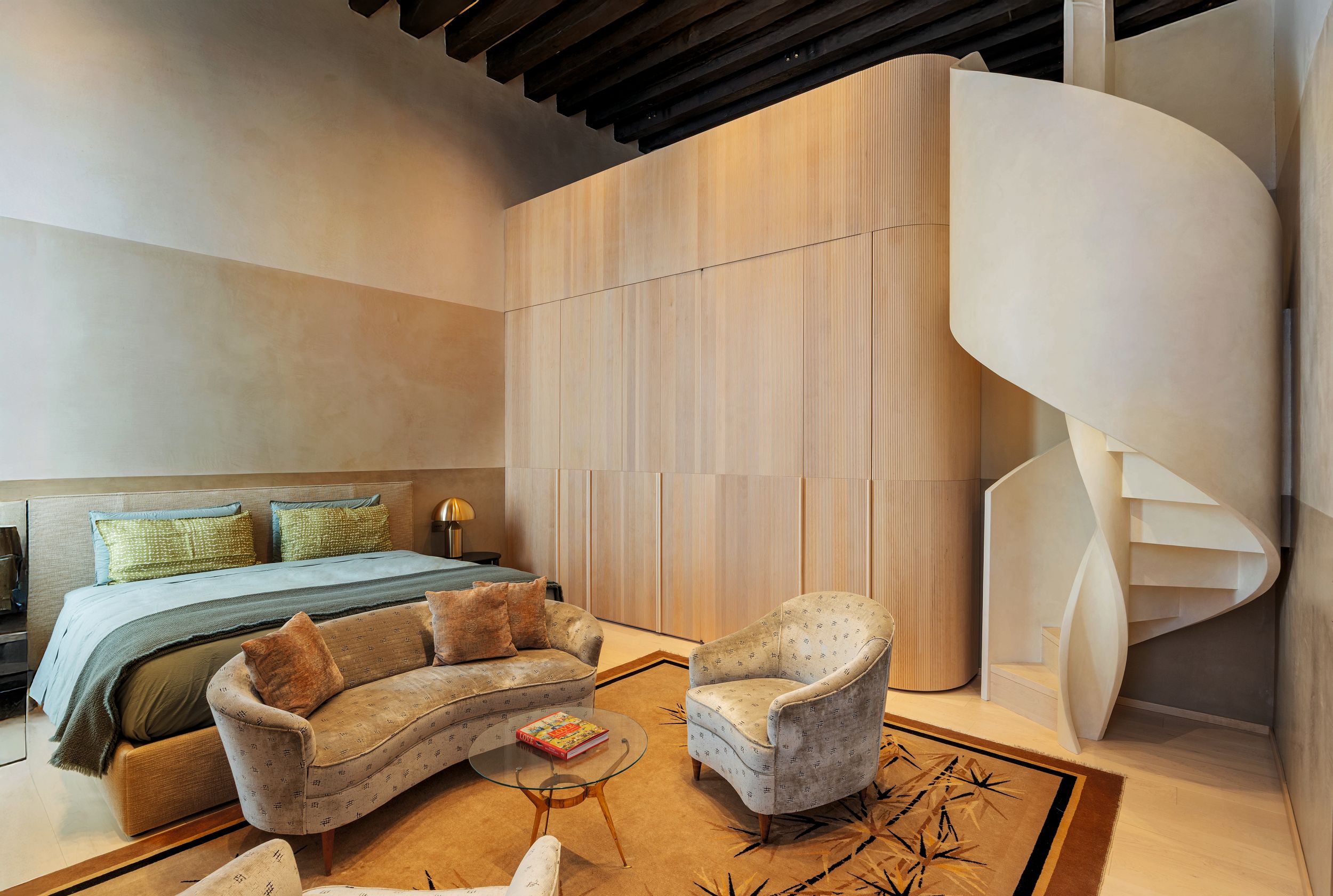 La habitación de su hijo, Kevin, se caracteriza por una decoración de grandes franjas horizontales en claroscuro. Para acceder al estudio y al gimnasio, situados en el entresuelo, hay una escalera de caracol de madera a medida, revestida de marmorino y arce. Un gran armario de madera acanalada oculta el paso hacia el baño y sirve al mismo tiempo de barandilla para el balcón que da al gimnasio