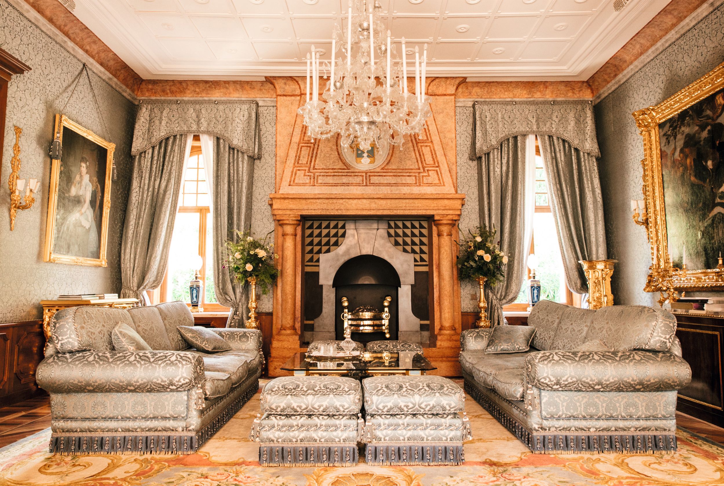 La opulenta sala de estar, presidida por una chimenea de gran presencia y una lámpara de araña veneciana antigua. El cuadro de la izquierda es un retrato de la Reina Margarita de Italia.