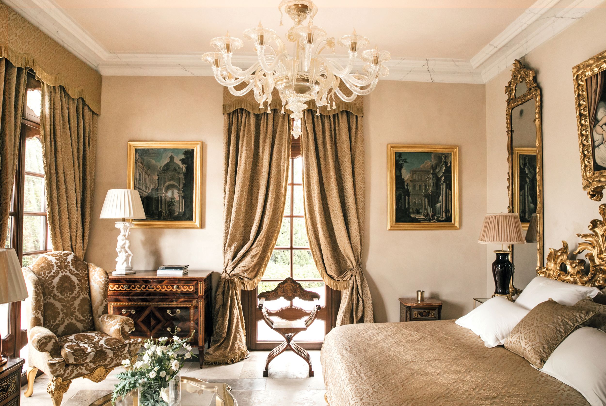 El dormitorio de una de las dos villas de invitados. La cama cuenta con un gran cabecero tallado en madera de principios del siglo XIX, y en las paredes cuelgan pinturas italianas del siglo XVII