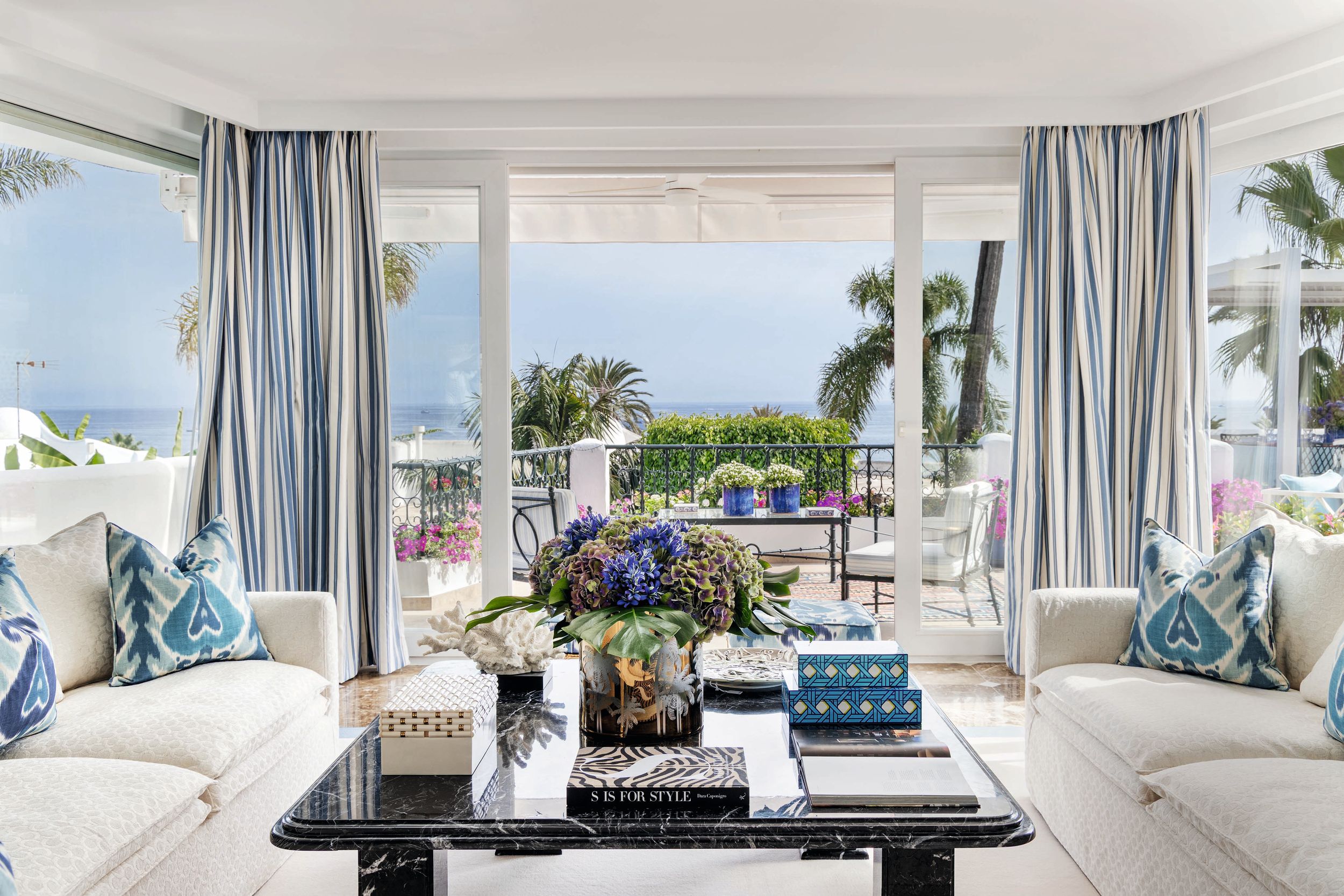 Una vista del salón, que se abre directamente a una gran terraza concebida como una extensión de la estancia. En él se combinan muebles de familia rediseñados para darles un toque contemporáneo con piezas modernas de estilo atemporal. Además, se han sumado lámparas de cerámica de inspiración china, tipo mayólica, consiguiendo que toda la decoración resulte muy fresca y marinera