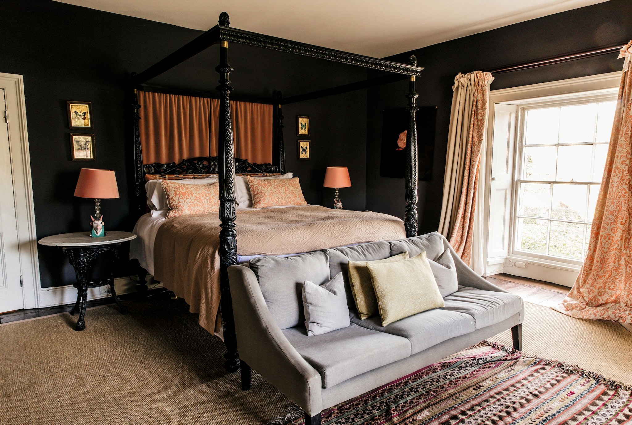 Habitación con dosel, sofá gris, ventana y decoración elegante