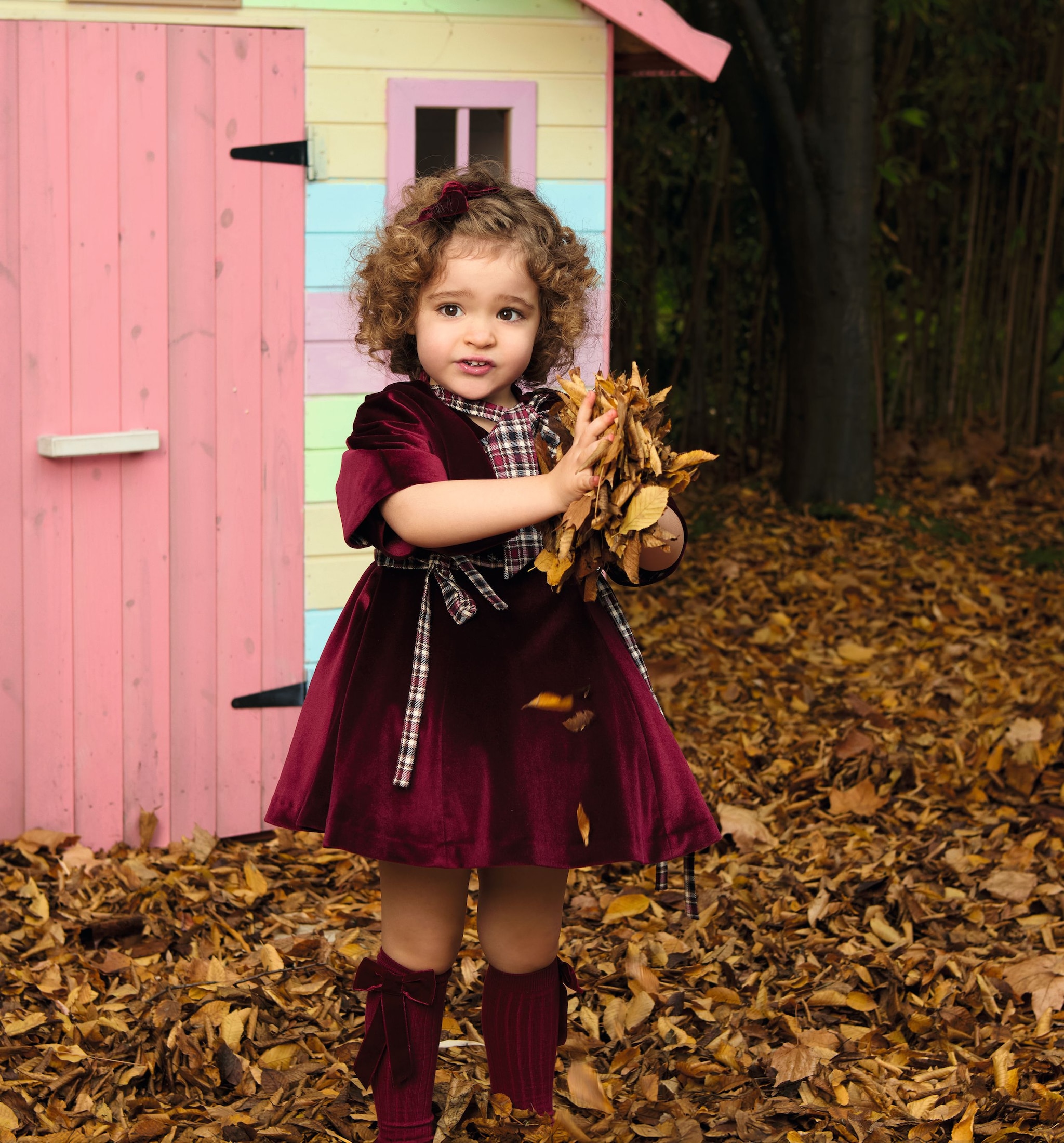 Anita con vestido de terciopelo jugando con hojas 