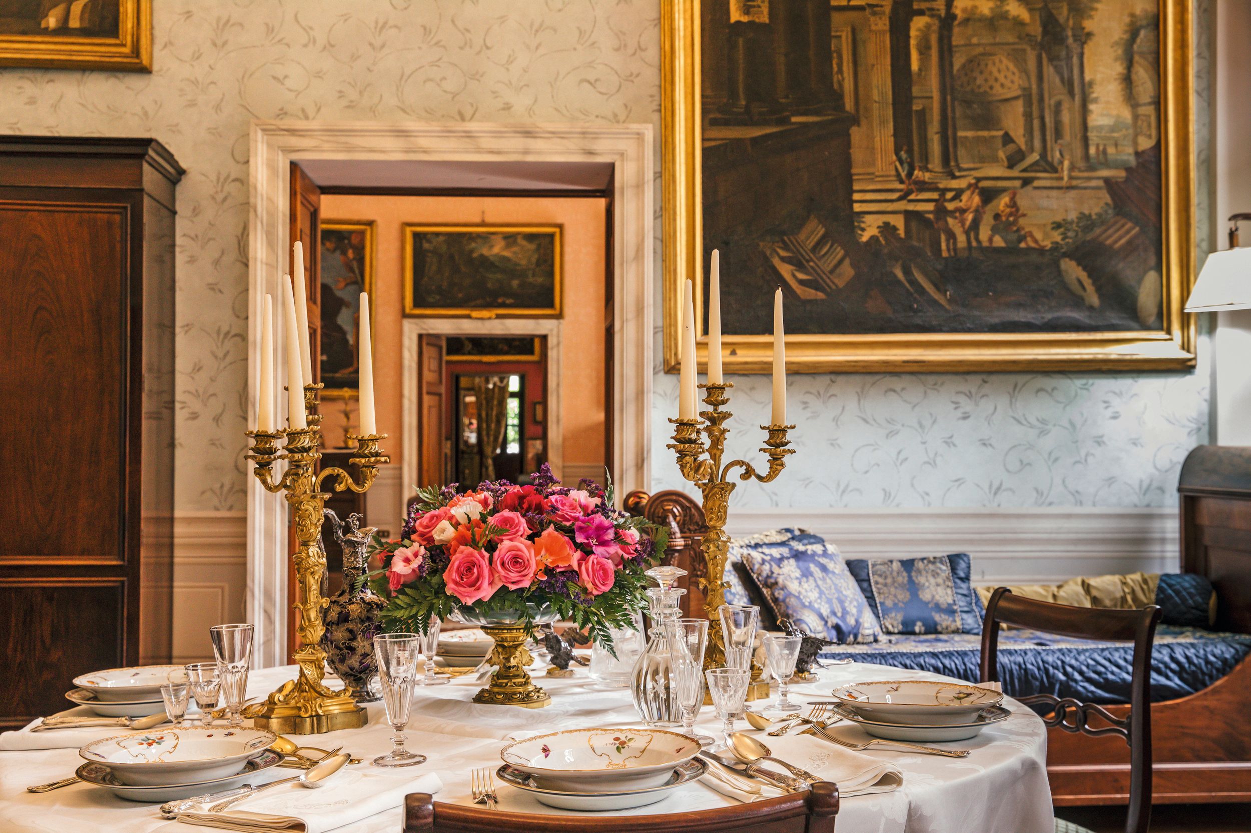 La mesa del gran salón, ataviada con un mantel de lino bordado con las iniciales del príncipe Alfonso, reúne cubiertos de época victoriana, porcelana de Meissen del siglo XVIII y cristalería de Baccarat del XIX grabada con el escudo familiar. Página siguiente, abajo, dos perspectivas más de este histórico espacio