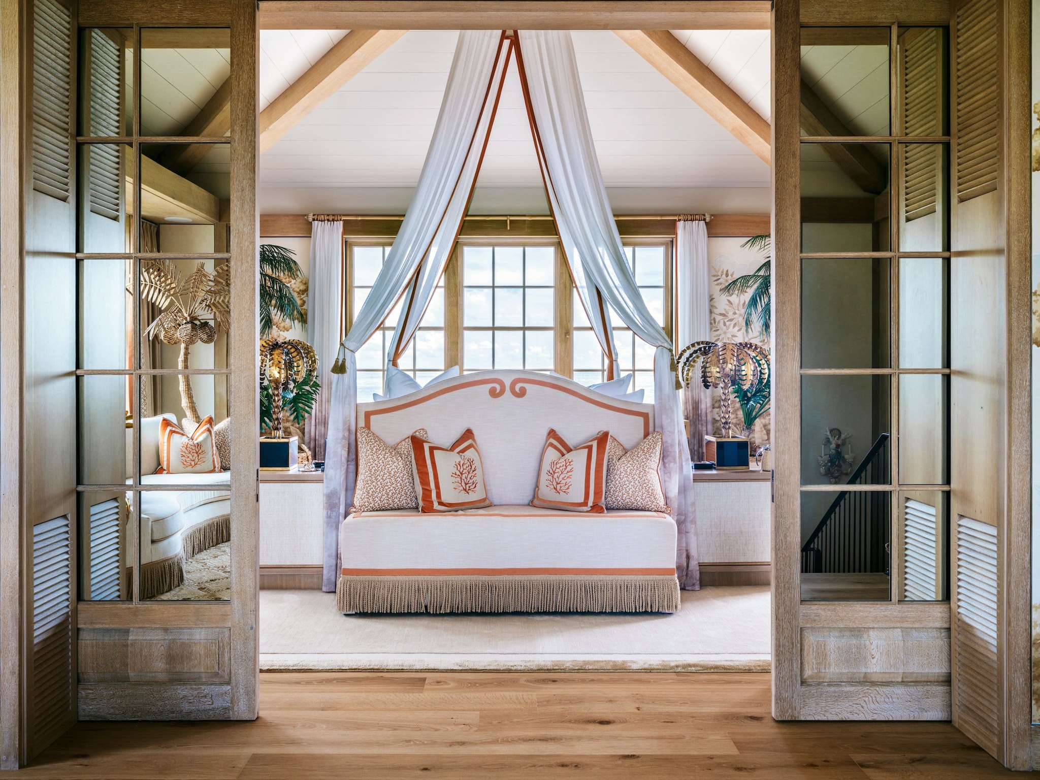 Habitación con cama bajo dosel, almohadas decorativas y ventanas grandes