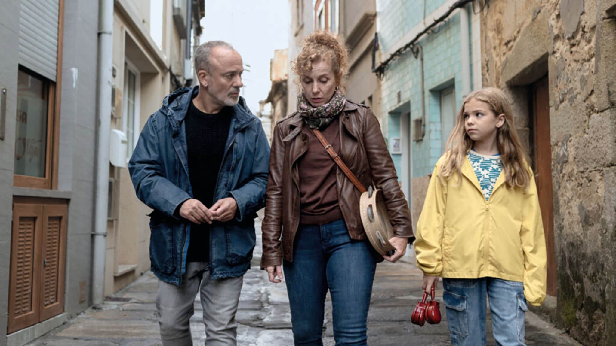 Javier Gutiérrez camina con una mujer y una niña por un callejón estrecho.