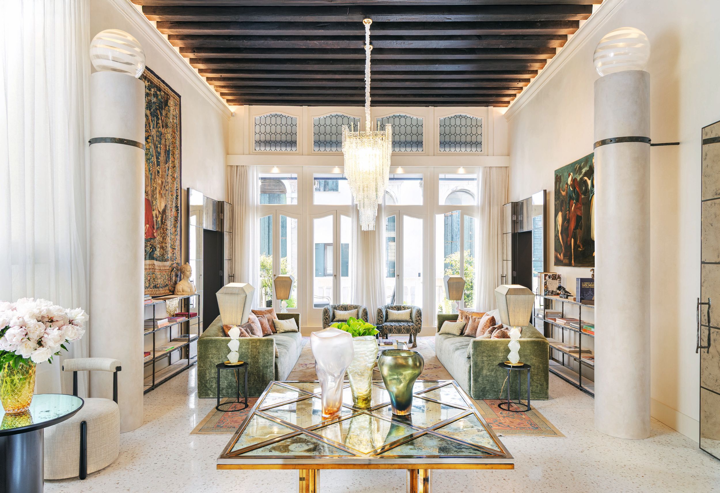 El salón, donde destacan columnas a medida, que integran un sistema de iluminación con globos "vintage" de cristal de Murano, atribuidos a Santillana; un cuadro del siglo XVI, y un tapiz del siglo XV de la colección privada del matrimonio. En el centro hay una mesa de Willy Rizzo de latón pulido, acero y espejos envejecidos