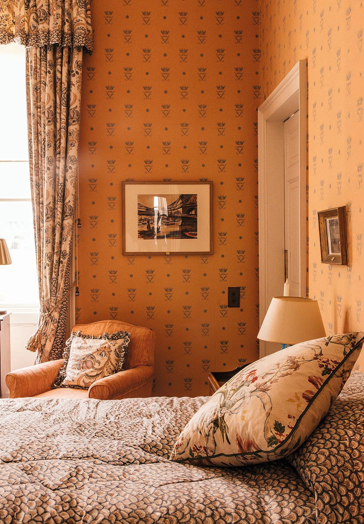 Habitación con cama, silla, lámpara y cuadros en la pared.