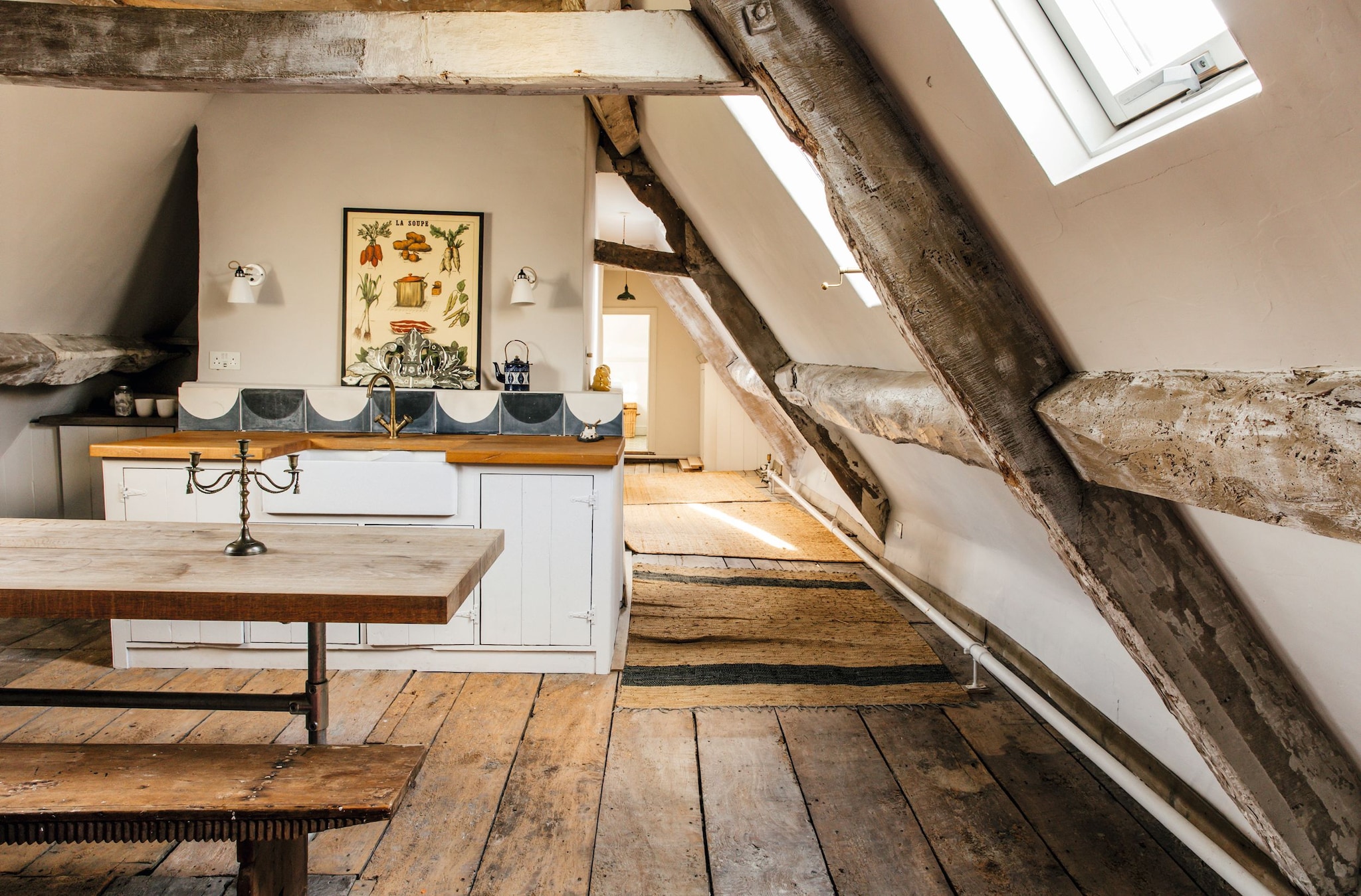 Ático rústico con vigas de madera, mesa de madera, cocina y ventana de techo