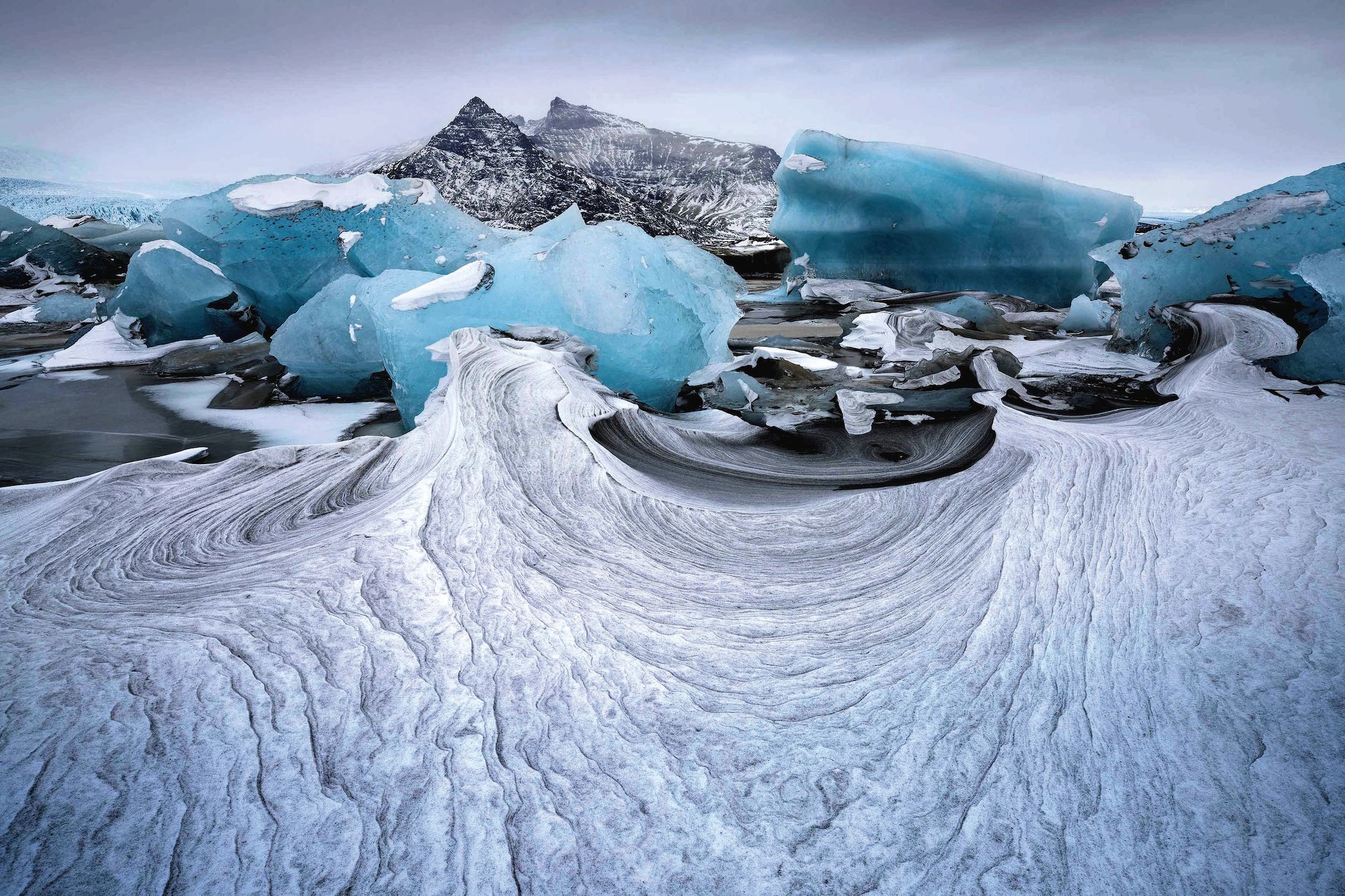 Paisaje ártico con icebergs azules y montañas nevadas al fondo