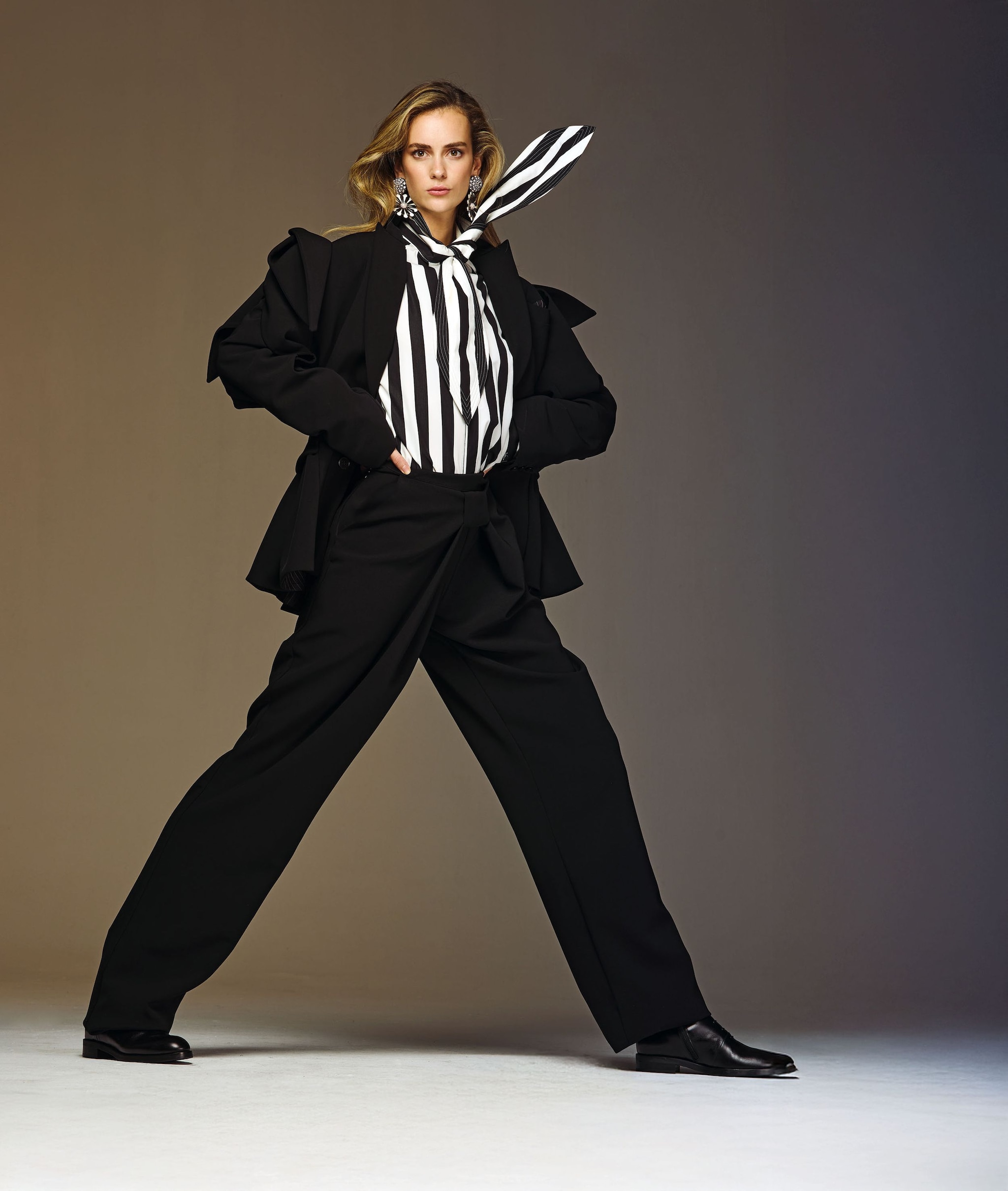 Gala Houlihan con chaqueta y pantalón negros y blusa a rayas