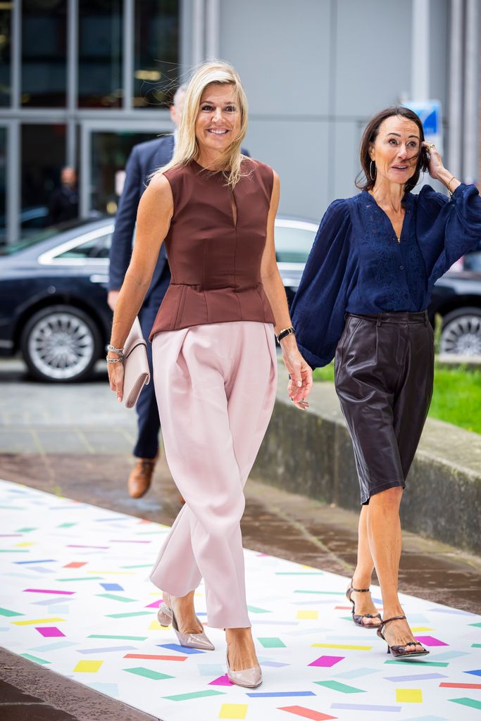 La reina Máxima con unos pantalones globo en tono rosa bebé.