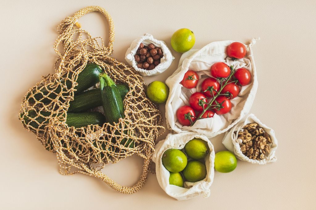 Bolsas de la compra reutilizables con materias primas saludables: tomate, nueces, limas y calabacines