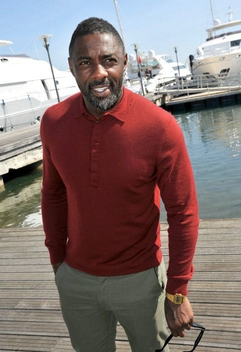 Idris Elba en Cannes el pasado mes de abril, con jersey de punto tipo polo de color rojo y pantalón chino caqui.
