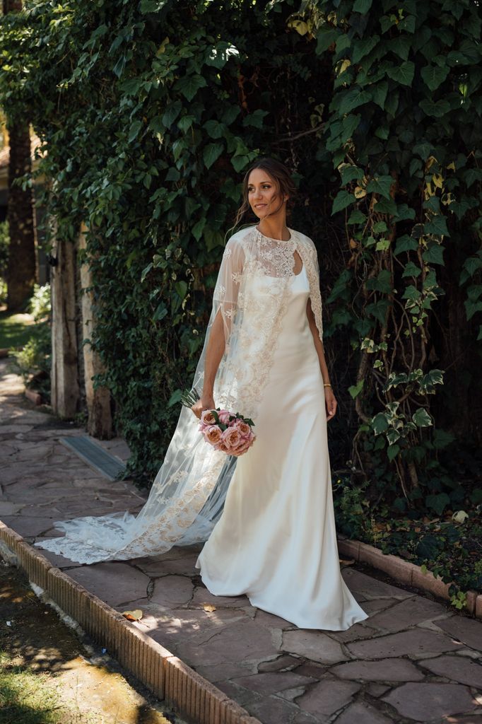 Novia con capa de encaje y vestido de Helena Mareque