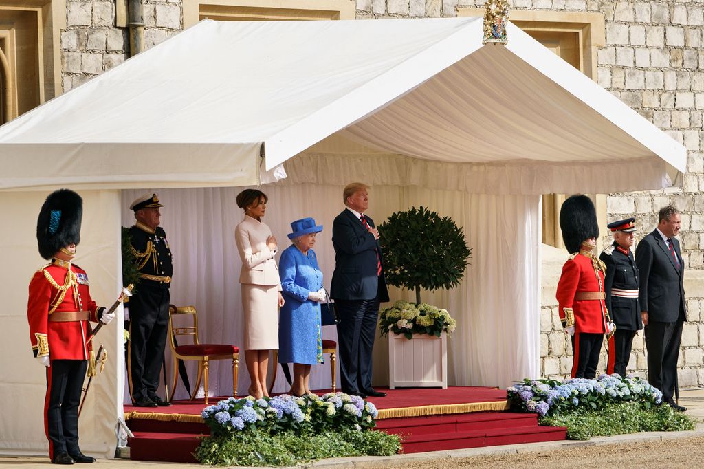 Plano general de la reina Isabel II con Donald y Melania Trump escuchando el himno de Estados Unidos