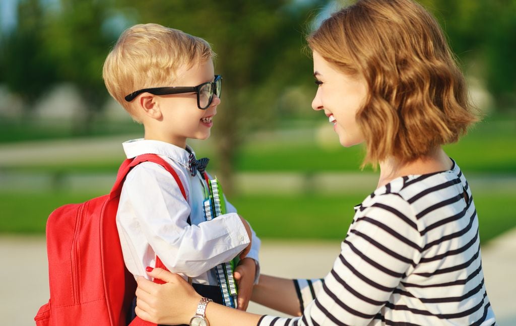 Madre acompañando a su hijo contento en el primer día de colegio
