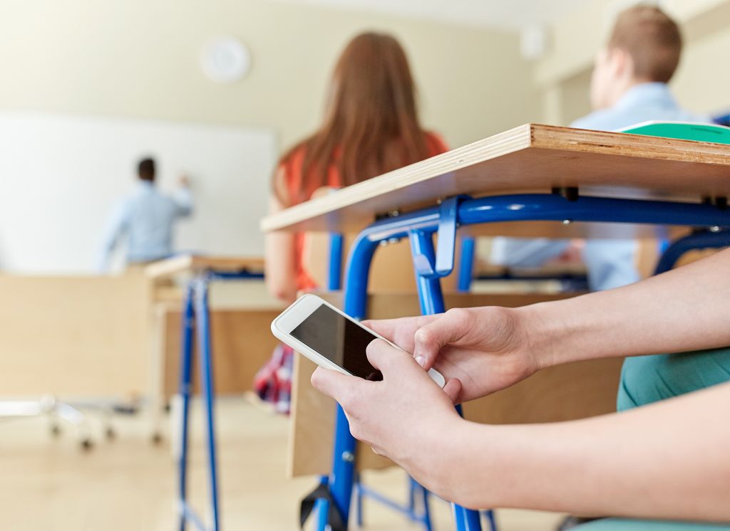 Adolescente mirando un móvil a escondidas en clase