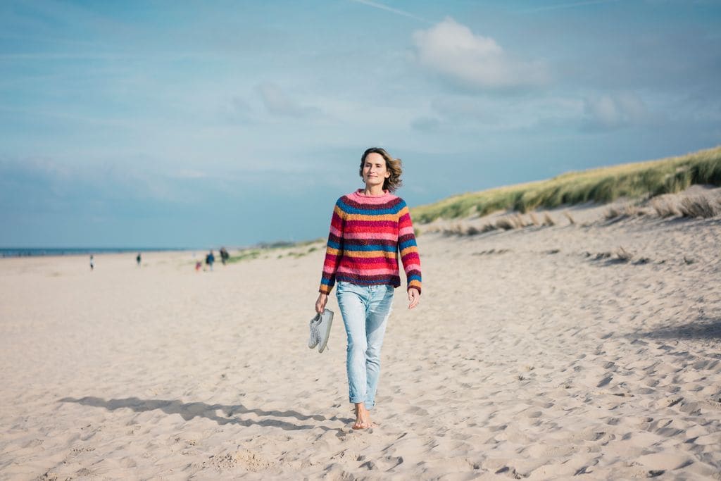 mujer madura caminando sobre la arena de la playa