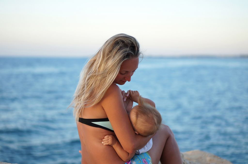 Madre dando el pecho a su hijo en la playa