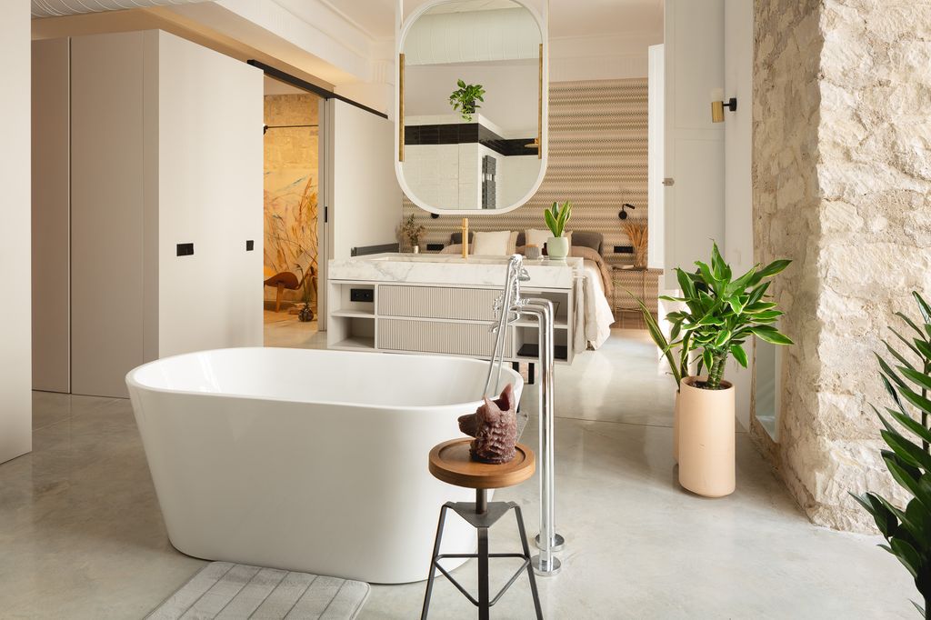 
Bañera exenta, módulo con la zona de cortesía del baño y, al fondo, el dormitorio totalmente abierto
