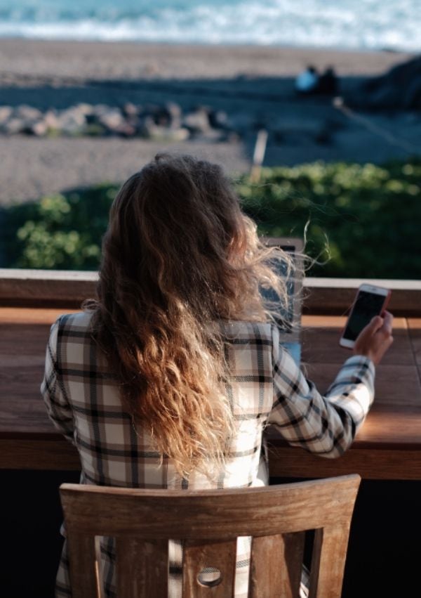 Mujer con ordenador y teléfono en su terraza
