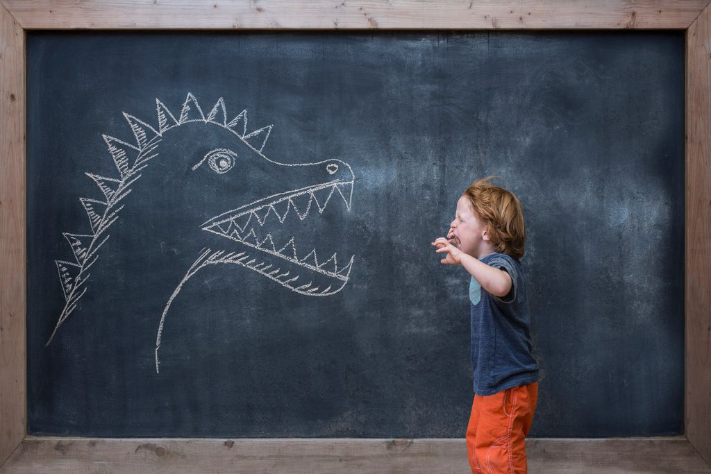 Niño pequeño con un dragón dibujado en la pizarra