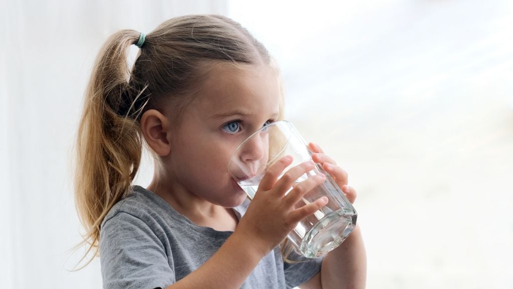 Niña con diabetes bebiendo un vaso de agua