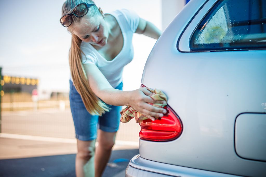 Una mujer lavando su coche