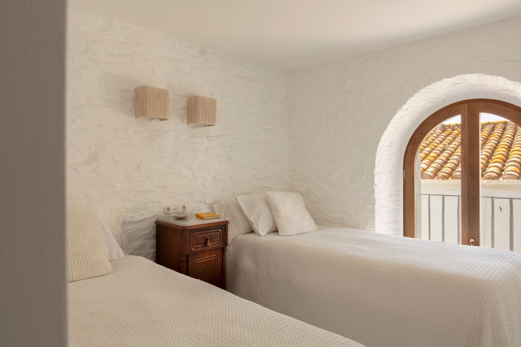 Dormitorio con paredes encaladas y ventana en forma de arco