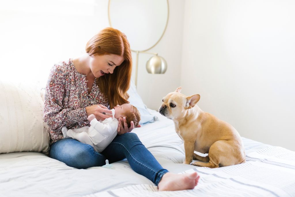 Una madre con su recién nacido en la cama, junto con su perro