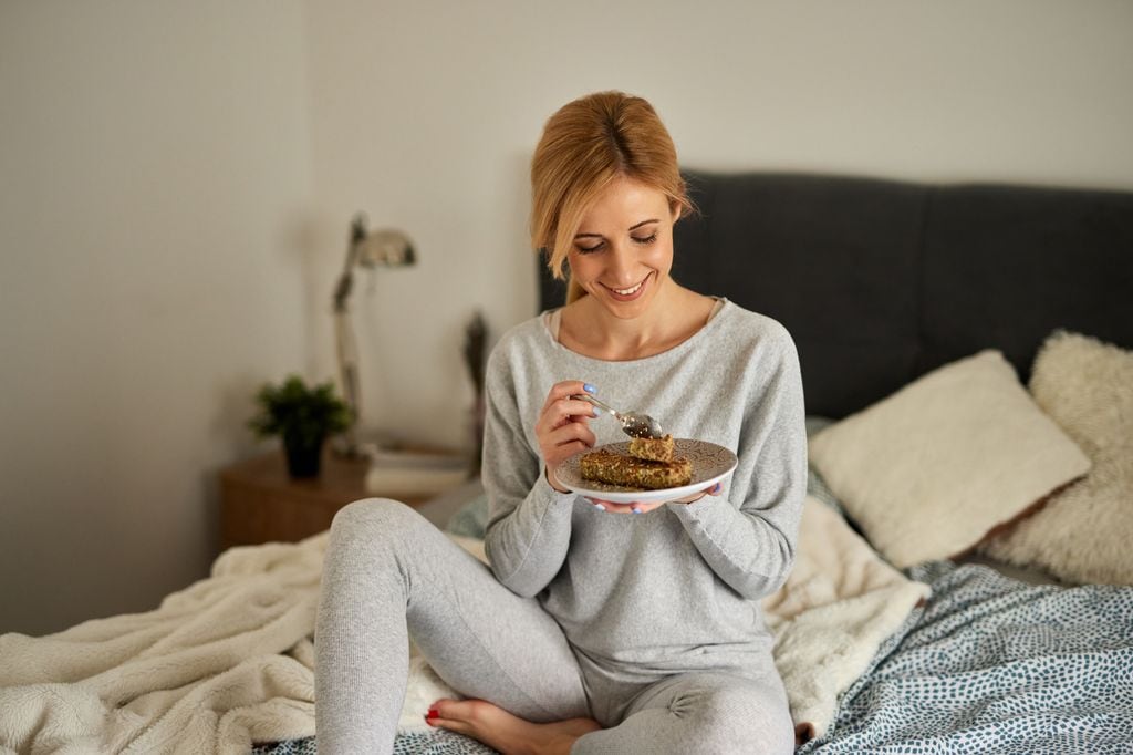 mujer comiendo sentada en la cama