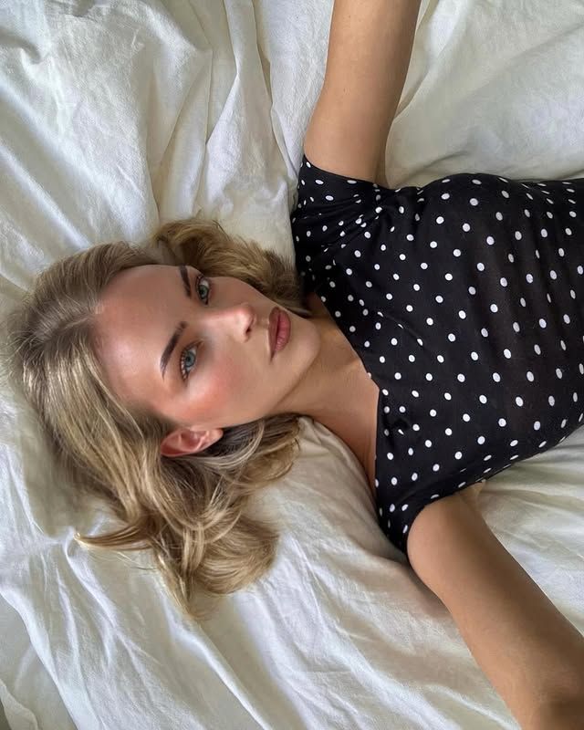 Emilia Silberg tumbada en la cama con top de topos y el pelo suelto