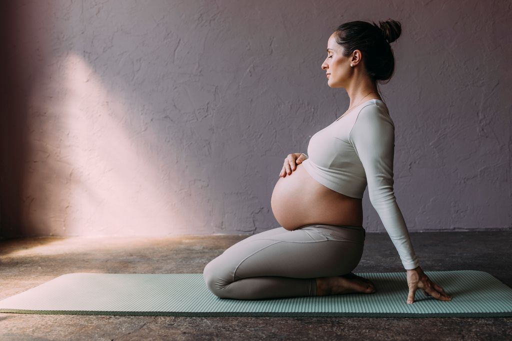 mujer embarazada respirando mientras hace yoga