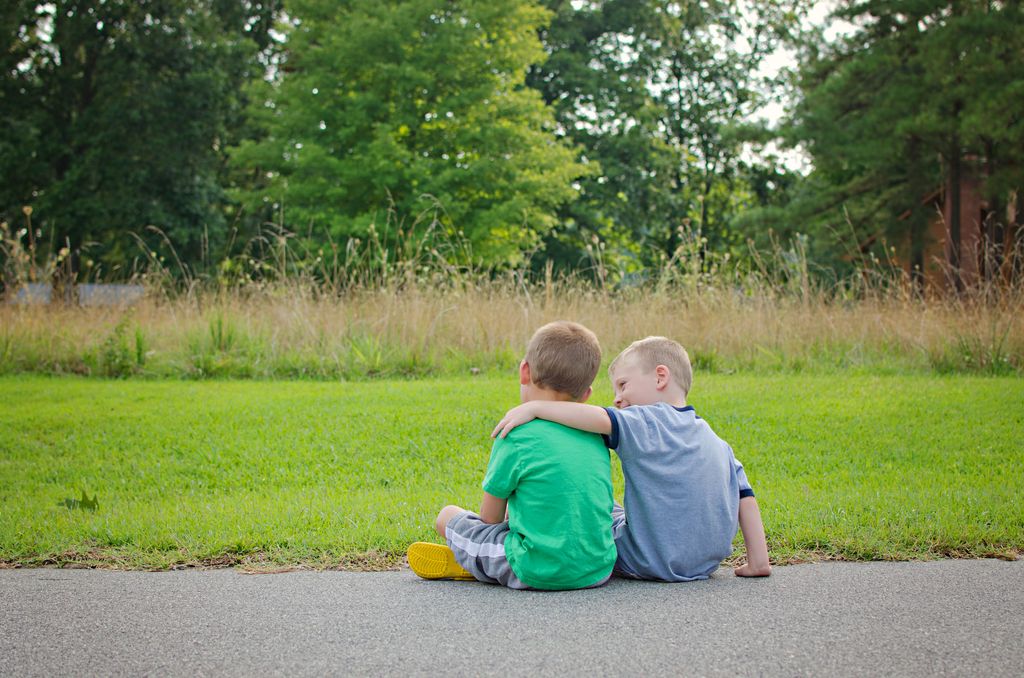 niños de espaldas, sentados en el suelo, dándose un abrazo
