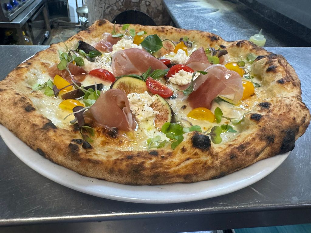 Pizza de higos con  jamón de Parma DOP Doble Corona, tomates cherry amarillos y rojos Piennolo del Vesubio DOP y ricota de búfala. 