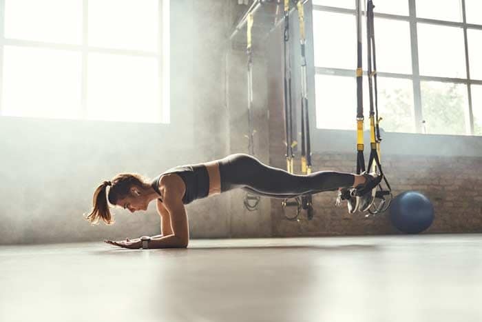 mujer haciendo ejercicio con los TRX