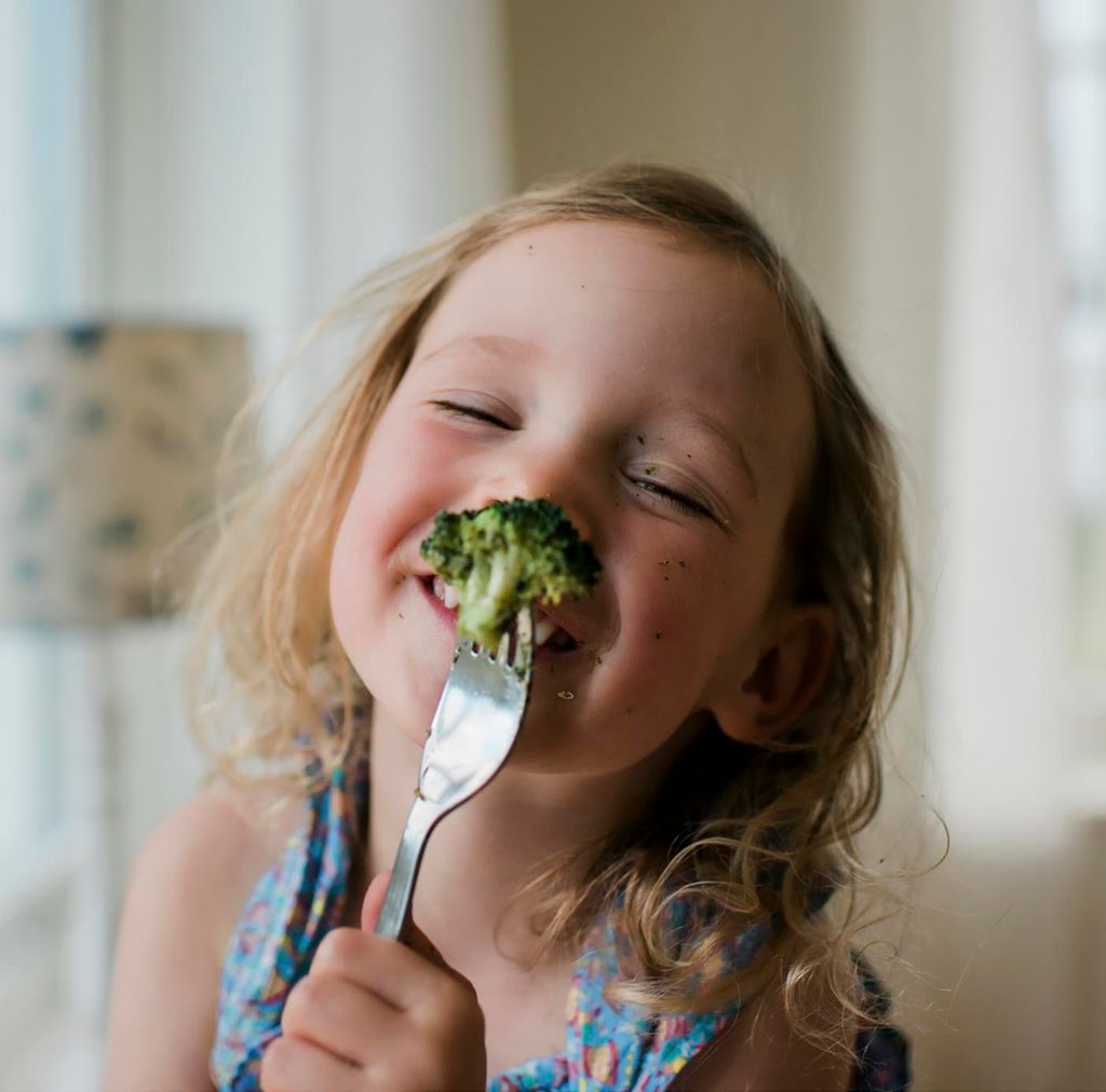 Niña come brócoli