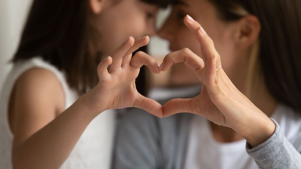 Madre e hija haciendo un corazón con la mano