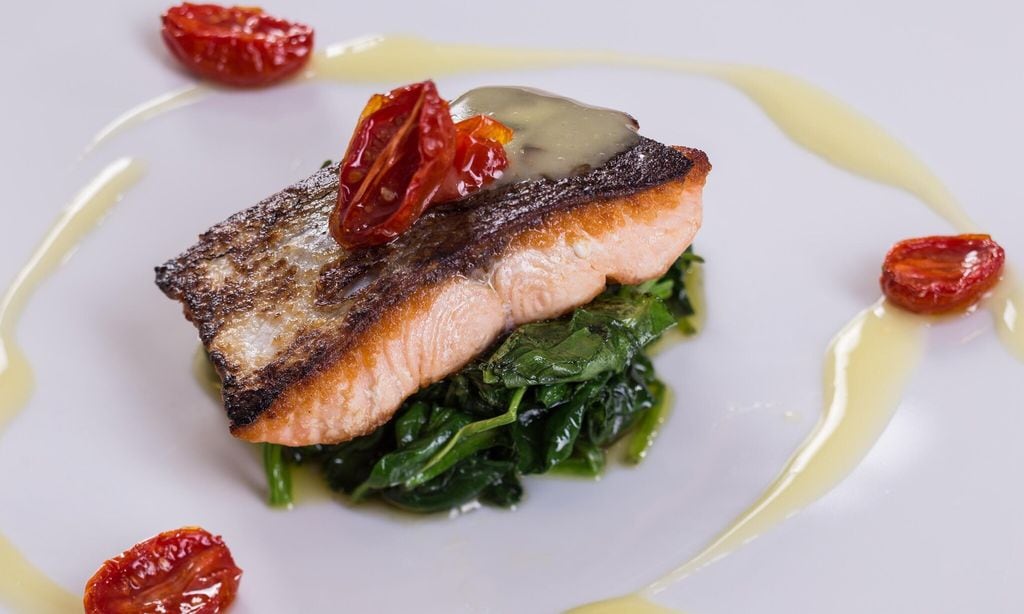 Plate of salmon steak on a bed of spinach and organic lemons cream. Trattoria Carnera restaurant. Vallagarina. Ala. Trentino. Italy. Europe