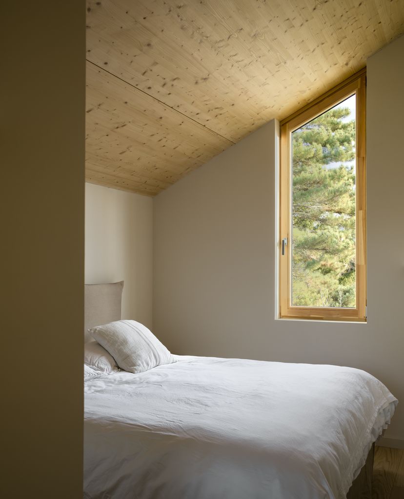 Dormitorio con techo inclinado forrado en madera