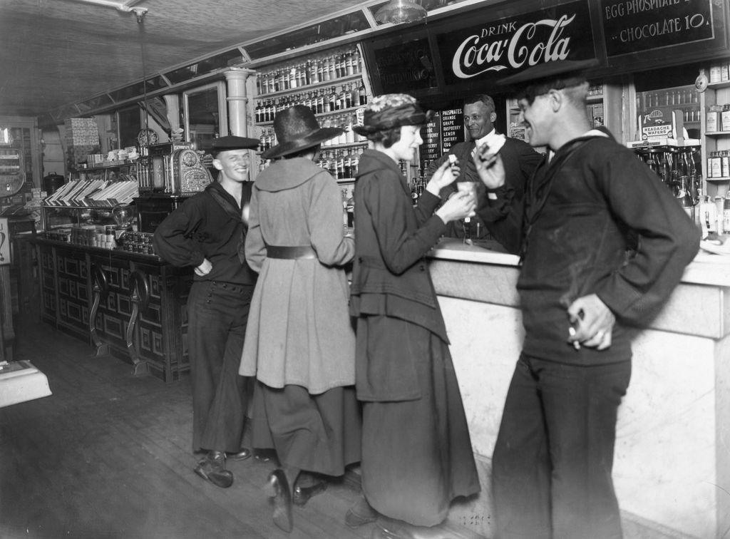 Dos marineros y sus acompañantes toman Coca-Cola en una fuente de soda durante la Primera Guerra Mundial, reflejo de cómo la bebida empezó a popularizarse entre los jóvenes estadounidenses a comienzos del siglo XX