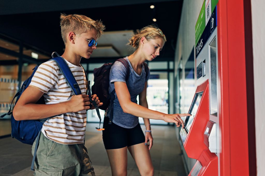 Adolescentes sacando un billete de tren un una estación
