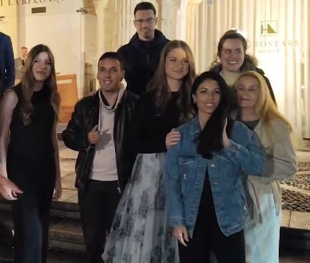 Plano medio de la Princesa Leonor e infanta Sofía haciéndose una foto con un grupo de fans en a la salida del Hotel Reconquista
