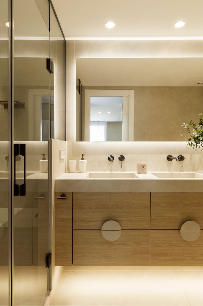 Baño con mueble de madera y espejo retroiluminado