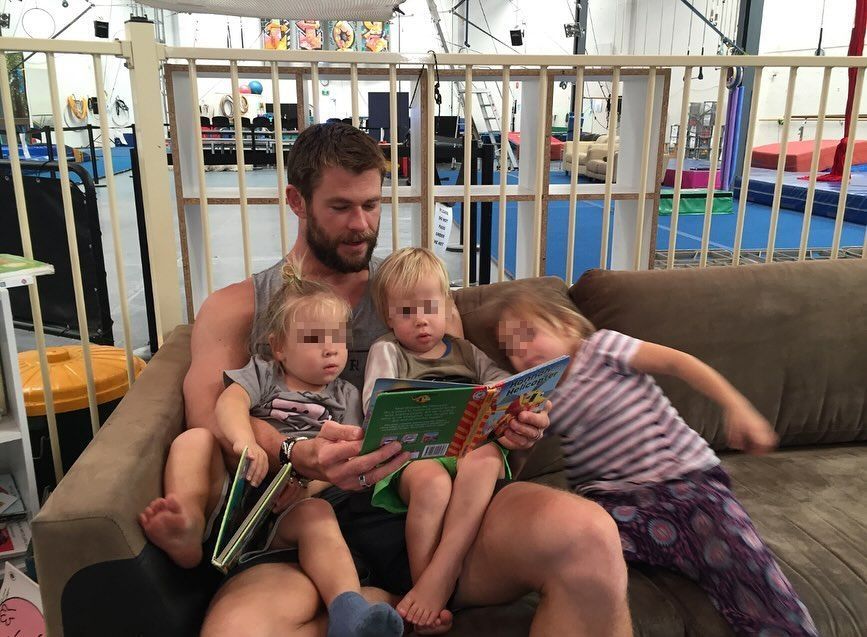 Plano medio de Chris Hemsworth contándole un cuento a sus hijos