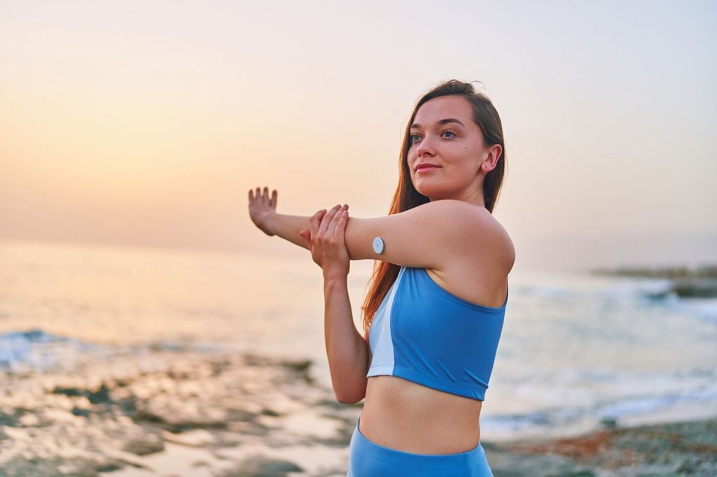 mujer diabética, con un dispositivo de control de la glucosa, en la playa
