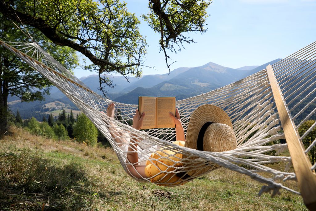 mujer en una hamaca en medio de la naturaleza leyendo un libro