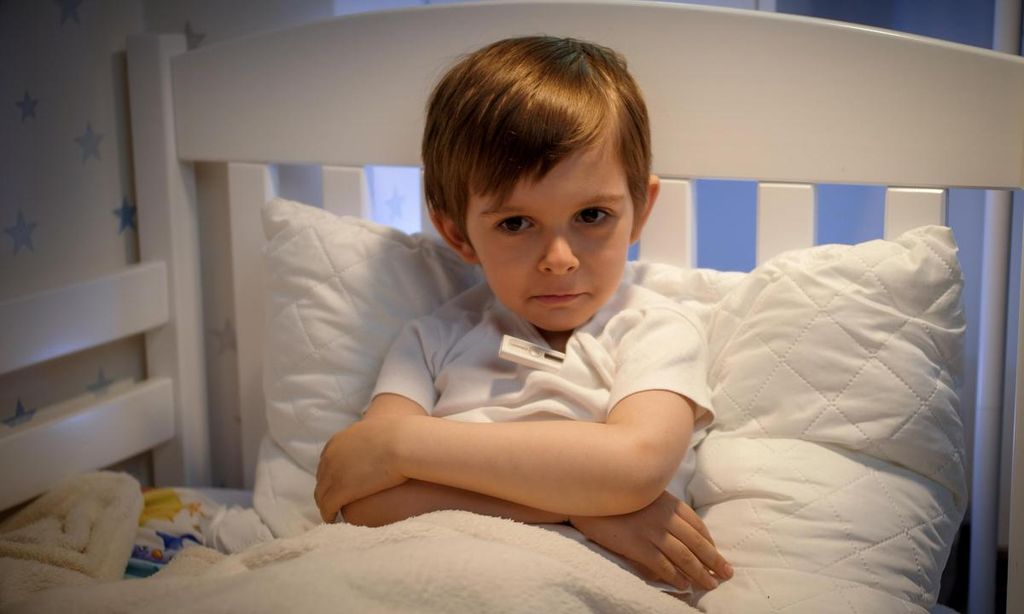 ni o enfermo sentado en su cama