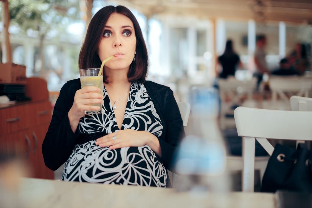 Embarazada tomando una bebida en un restaurante