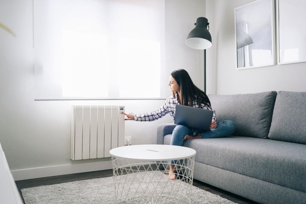 Mujer en casa comprobando un radiador de la calefacción de su casa